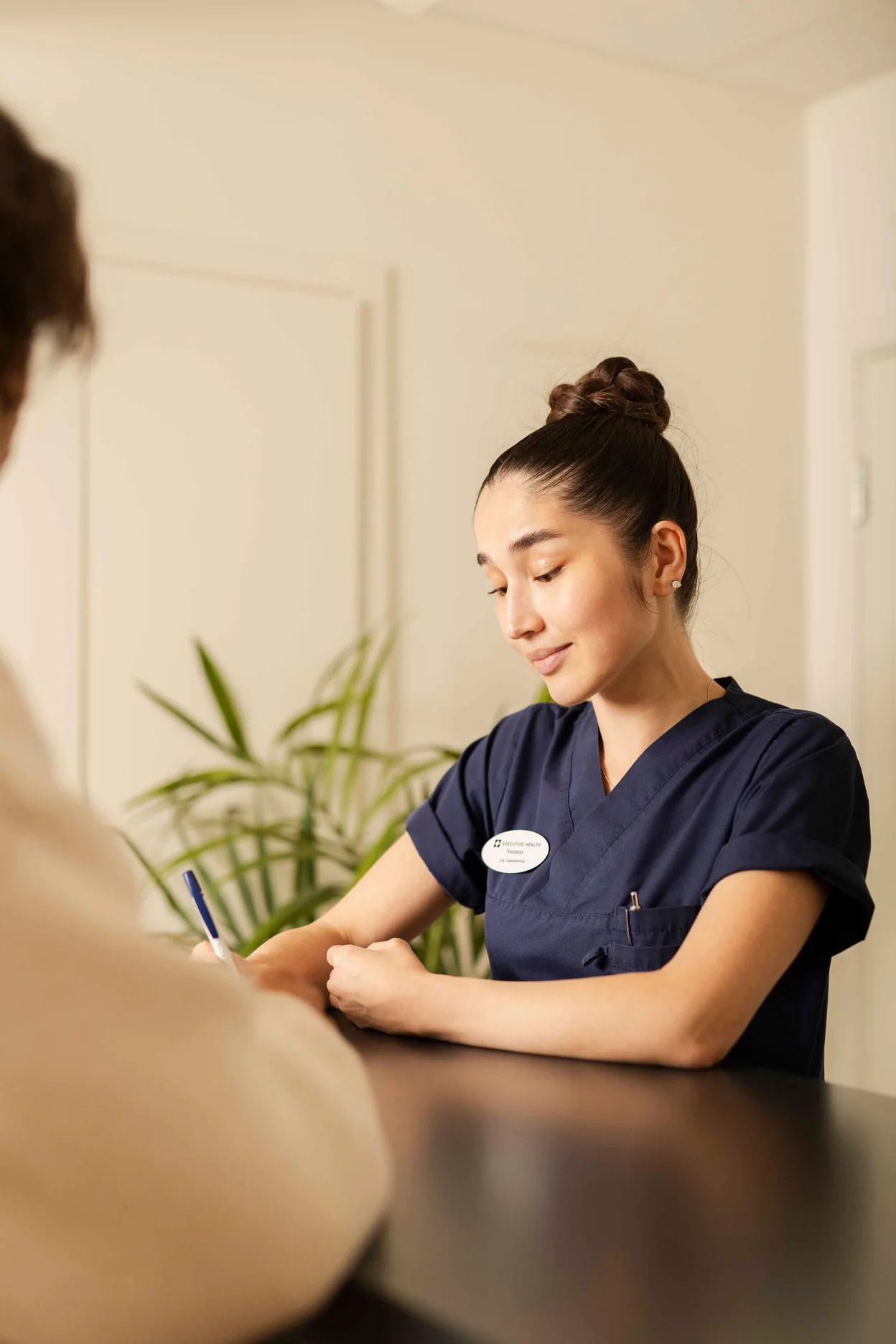 Clinician at Executive Health taking notes during a private patient intake consultation.