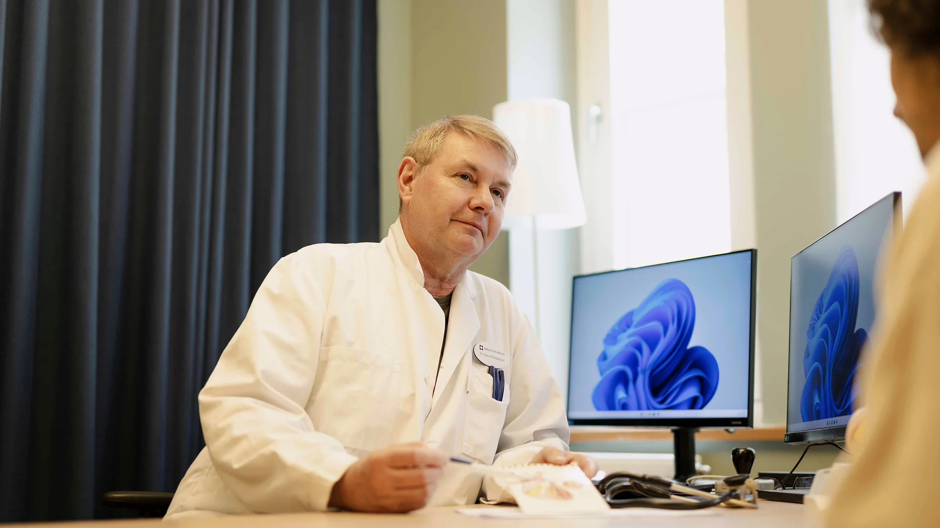 Executive Health doctor consulting with a patient in a clinical room.